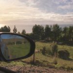 A Hill and tree view from a car window